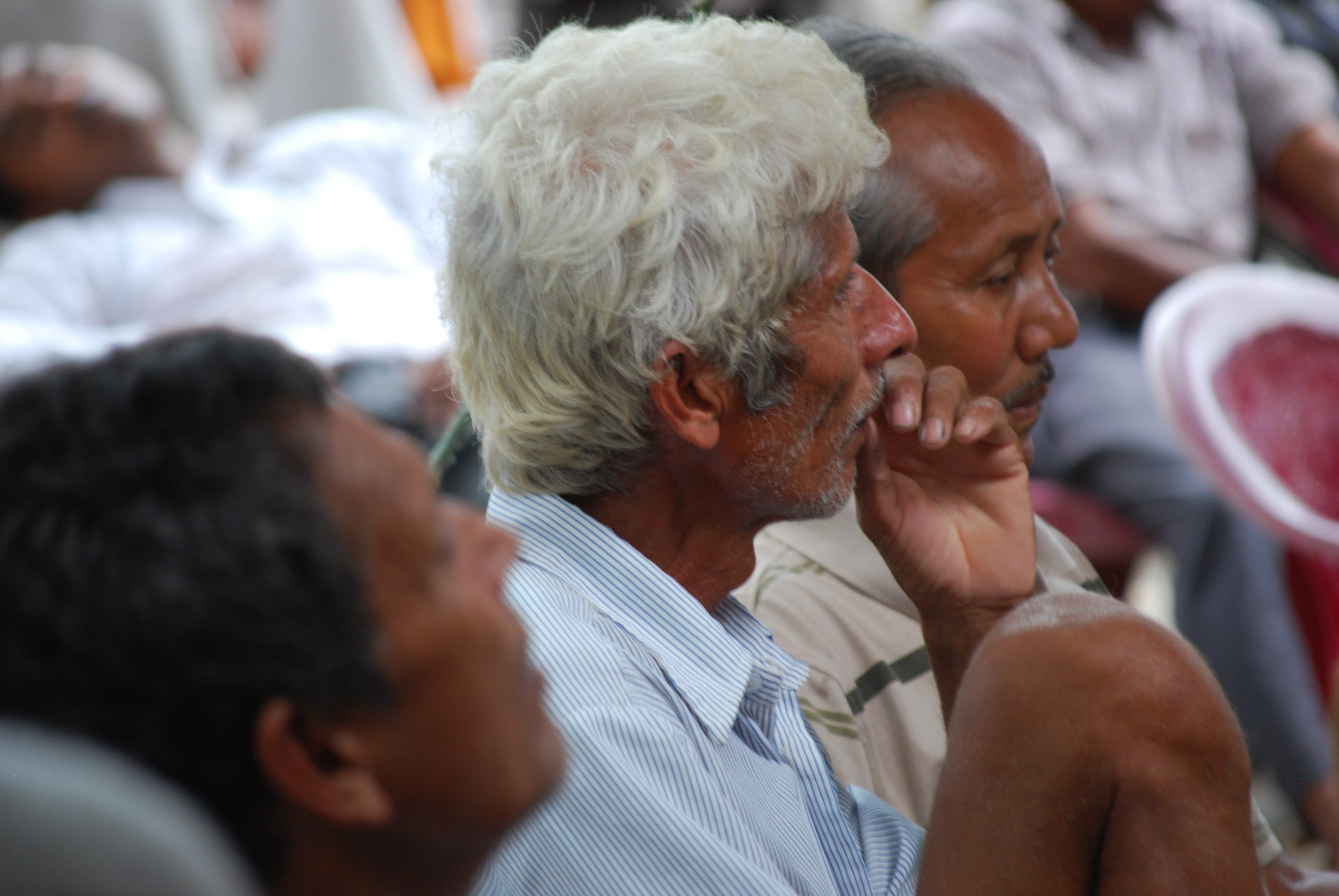 Man with white hair in an audience.