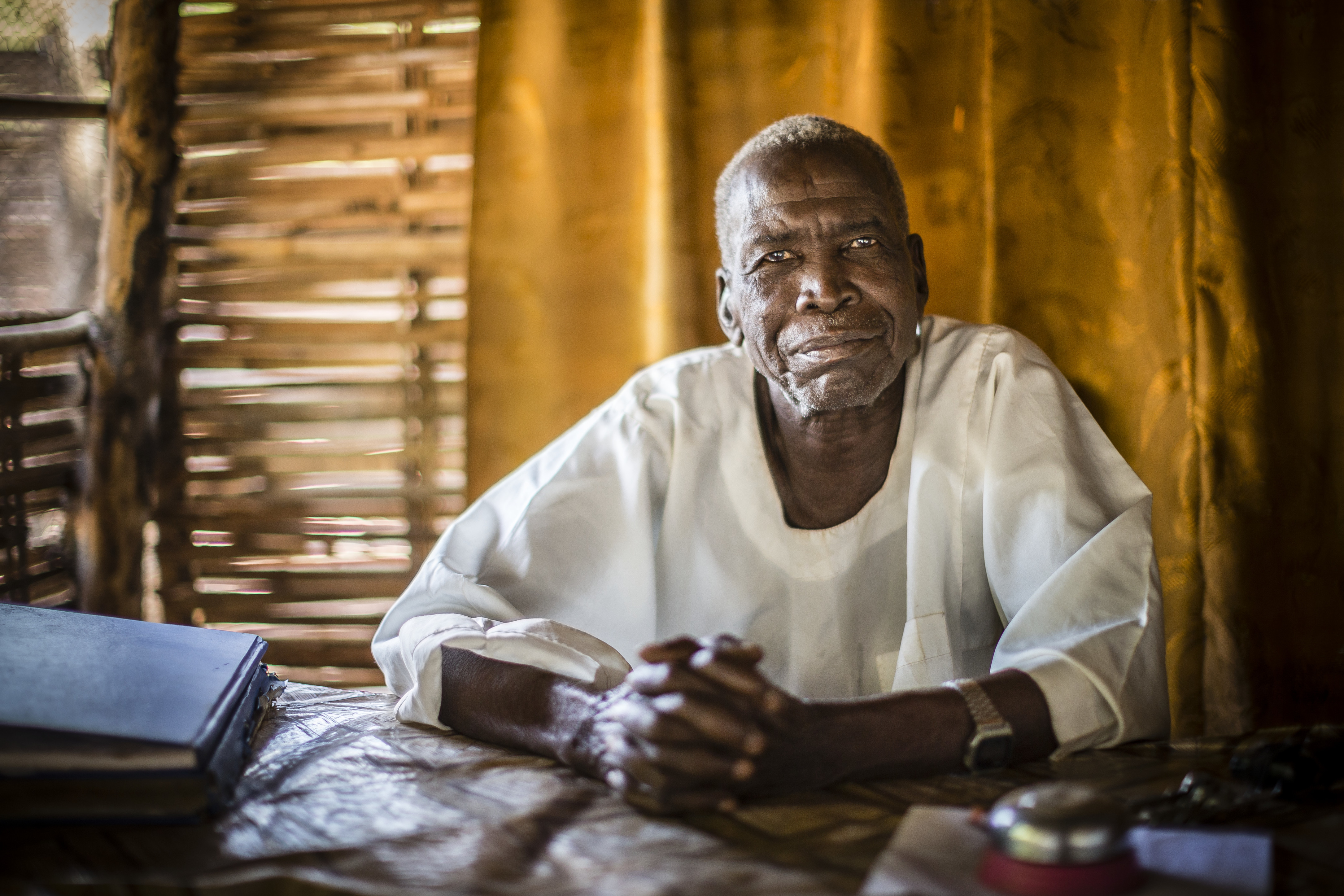 Portrait of Judge Chief Maktab seated at a desk in front of a cloth covered wall.
