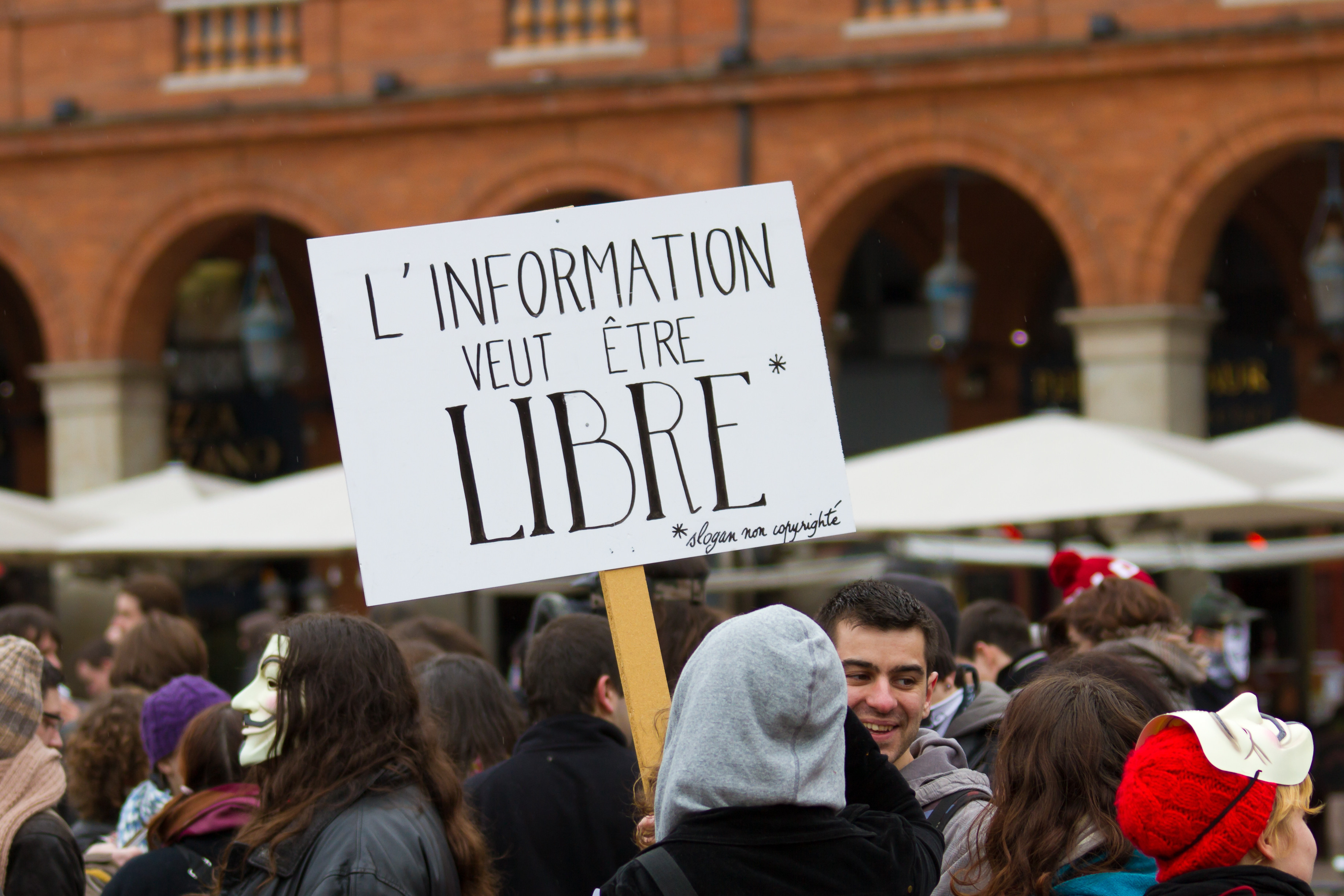 Crowd of protestors with one sign visible reading: L'information veut être libre